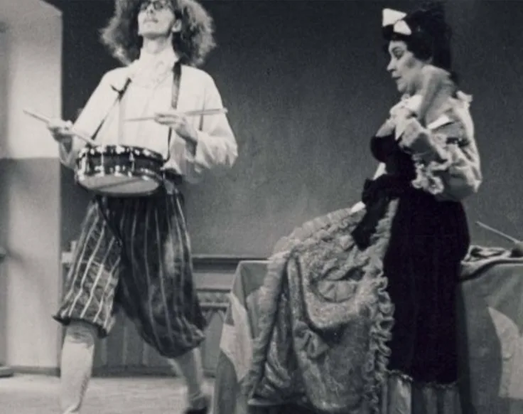 Young Ants Lusti on stage with a drum, beside Marika Vaarik in a rococo costume, in the production „Kuningal on häda”